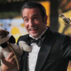 Best actor winner Dujardin of France carries Uggie the dog after "The Artist" wins the Oscar for Best Picture at the 84th Academy Awards in Hollywood
